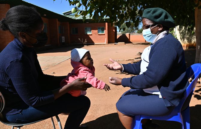 Health-care assistant Thapelo Makgokgowe visits a mother and her child in a clinic in Gaborone, Botswana, in May 2022.