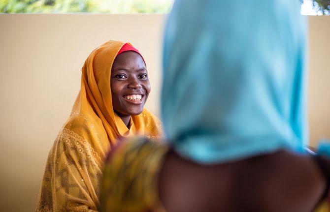 Wansama Johnson, a young woman living with HIV, sensitizing a client, right, at a care and treatment clinic. Kigamboni, Dar es Salaam, Tanzania, 1 October, 2019. Credit: UNAIDS/D.Msirikale