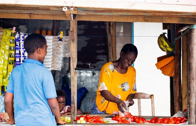 13 November, 2020 - Temeke, Dar es Salaam, Tanzania -  Caroline Damiani with a customer at her grocery store.